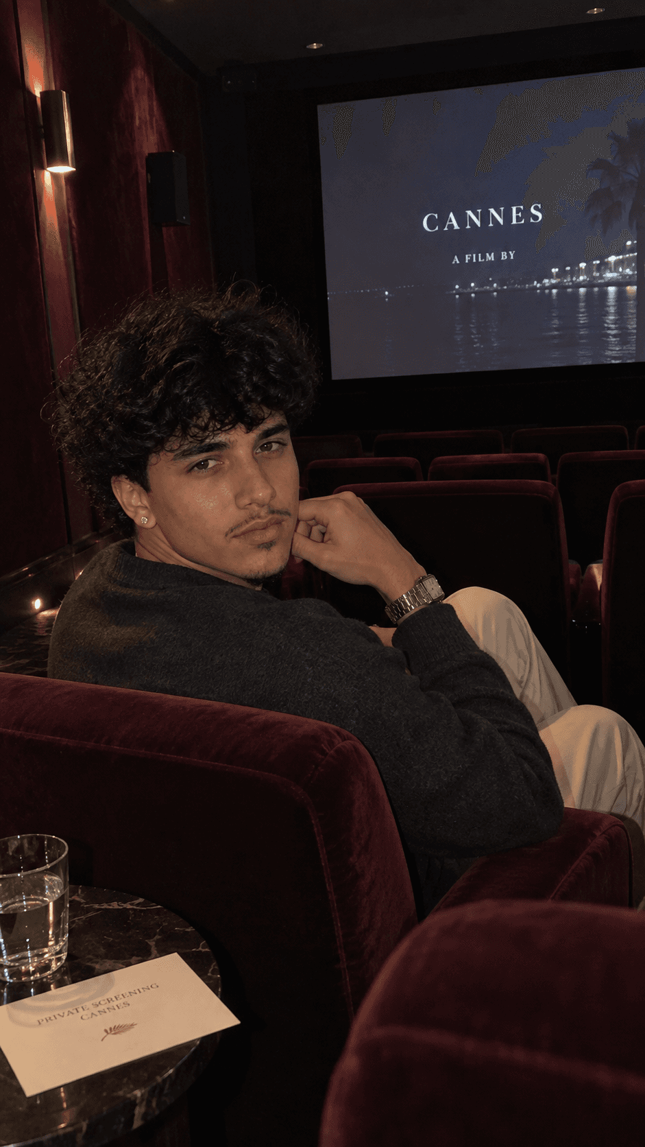 AI-generated man seated alone in a velvet private screening room in Cannes